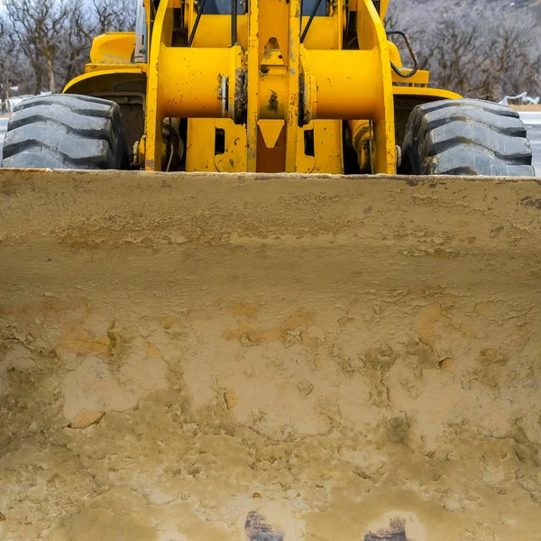 Square Dirty bucket of a bright yellow loader with huge black wheels — Stock Photo, Image