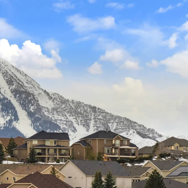 Marco cuadrado Vista exterior de casas con techos inclinados contra montaña y cielo azul nublado — Foto de Stock