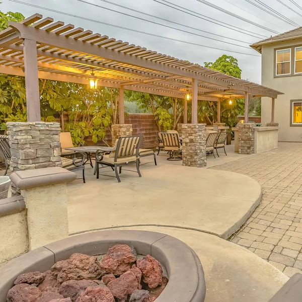 Square frame Patio with dining area and built in circular benches wrapped around a fire pit