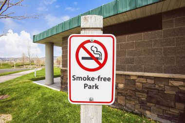 Bir Smoke Free Park işareti agianst taş duvarlı bir binanın görünümüne yakın