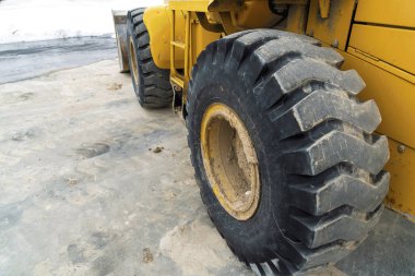 Sarı bir inşaat makinesinin siyah kauçuk tekerleğinin yakından görünümü