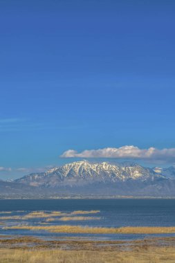Kar tepeli dağ ve sakin göl üzerinde kabarık bulutlar ile Canlı mavi gökyüzü
