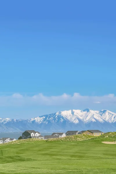 Wohngebiet mit Blick auf einen See und schneebedeckten Berg unter blauem Himmel — Stockfoto