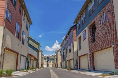 Güneşli bir günde mavi gökyüzünün altında ortasında asfalt yol ile evlerin Satır