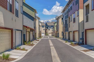 Karla kaplı dağ ve bulutlu gökyüzü manzaralı evlerin ortasında Yol