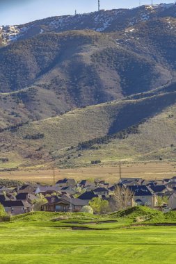 Güneşli bir günde görülen yükselen bir dağın tabanına yakın yerleşim alanı