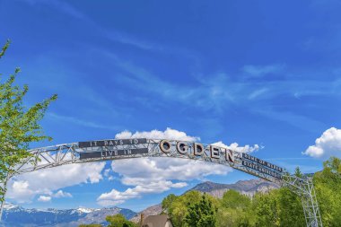 Welcome arch at the city of Ogden Utah against vivid blue sky and puffy clouds clipart