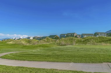 Mavi gökyüzünün altında otlarla kaplı uçsuz bucaksız bir arazide kıvrılan beton yol