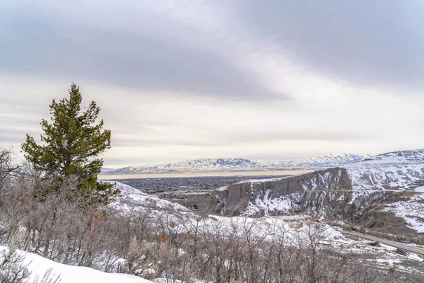 Montaña cubierta de nieve con carretera con vistas a un valle bajo el cielo nublado en invierno — Foto de Stock