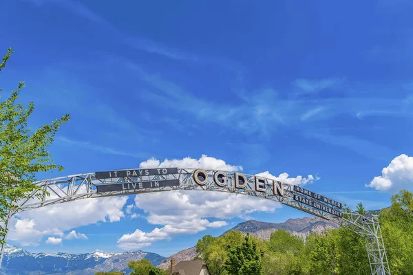 Welcome arch at the city of Ogden Utah against vivid blue sky and puffy clouds
