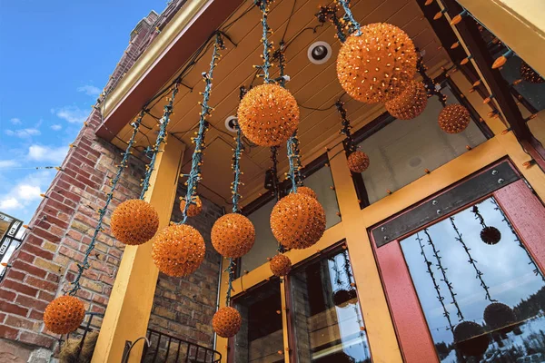 Boules de lumière orange suspendues à l'entrée d'un bâtiment avec mur de briques rouges — Photo