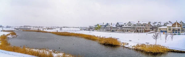 Bostadsområde med utsikt över en sjö med Grädda och snöiga stranden på vintern — Stockfoto