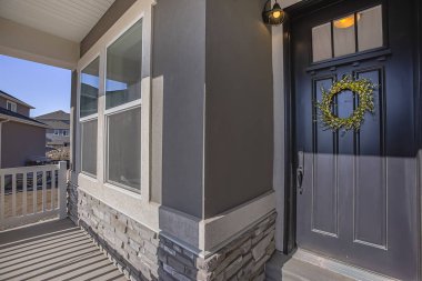 Pencere nin önünde güneşli bir veranda ve cam paned kapı ile ev cephesi