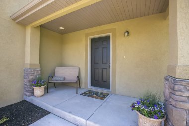 Verandada bank ve saksı çiçekli bitkiler ile bir ev girişi