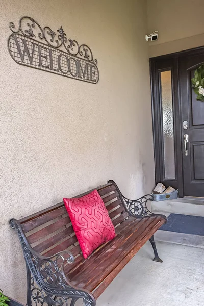 Rustic metal and wood bench with red pillow on the porch of a home