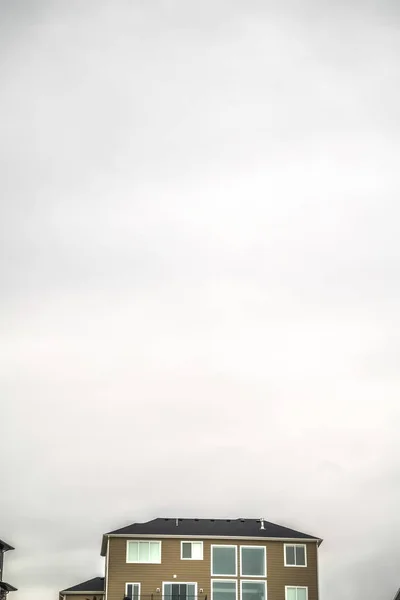 Heller und wolkenverhangener Himmel über einem Wohnhaus mit braunen horizontalen Wandanschlüssen — Stockfoto
