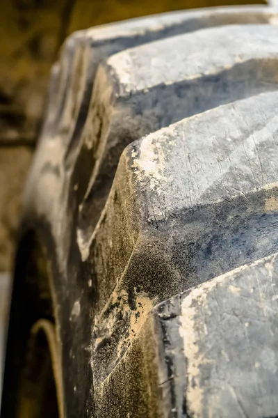 Close up of the dirty black rubber tire of a heavy duty construction vehicle — Stock Photo, Image