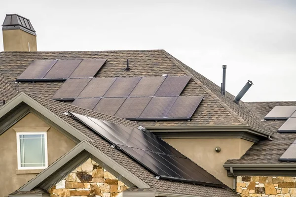 Pannelli solari sul tetto a falde scure di una casa con pietra e muro di cemento — Foto Stock