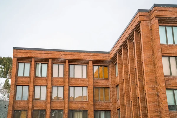 Exterior of red brick building with flat rooftop and shiny sliding windows