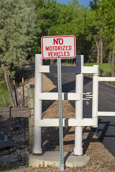 No hay señal de vehículo motorizado contra una puerta blanca y carretera estrecha en un día soleado — Foto de Stock