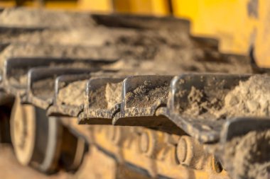 Güneşli bir günde sarı bir konstrüksiyon makinesinin metal grouser pedini kapatın