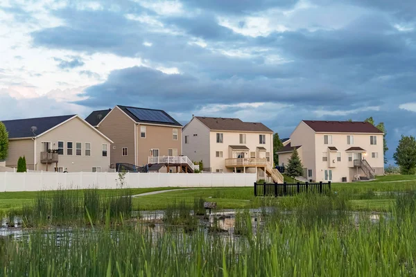 Çok katlı evlerin önünde bir alanın ortasında köprü ile Çimenli gölet