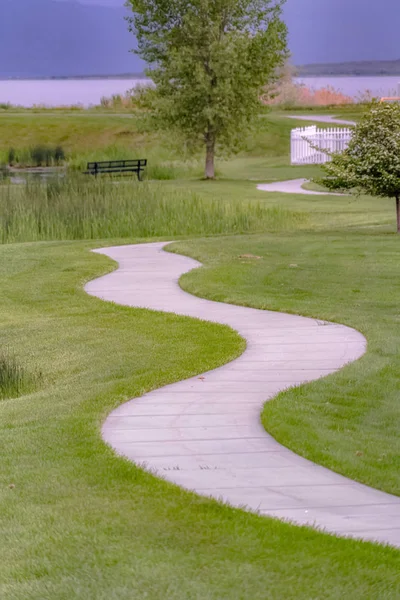 Arka planda bir gölet ve tezgah ile çimenli arazi ile eğri yol