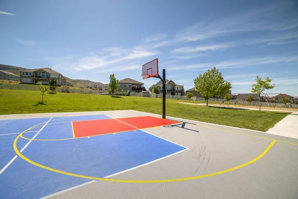 Открытый общественный баскетбольная площадка с домом горы и голубое небо фоне — стоковое фото