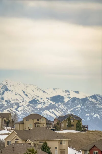 Vista de invierno de un barrio en una colina contra la montaña y un cielo nublado — Foto de Stock