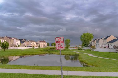 Arka planda gölet çimenli arazi ve evleri ile Herhangi bir zamanda işareti Park Yok