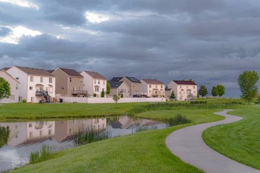 Balkonlu ve metrelik evlerin önünde köprülü park yolu ve gölet