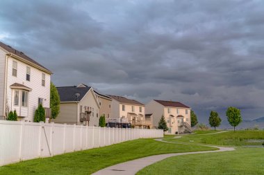 Döşeli bir yol ve gölet ile geniş bir yeşil alana bakan ev cephesi