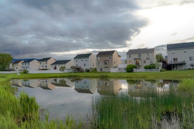 Aile evleri ve parlak bulutlu gökyüzü parlak mahalle gölet yansıyan