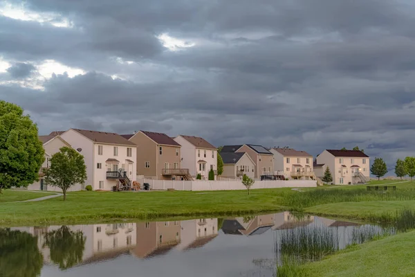 Parlak bir gölet ve geniş çimenli alan manzaralı güzel evler