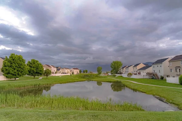 Rasenpark mit Teich und Wegen inmitten schöner mehrstöckiger Häuser — Stockfoto
