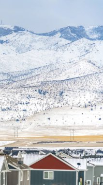 Dikey çerçeve Kışın karla kaplı gökyüzü ve dağa karşı evlerin dış