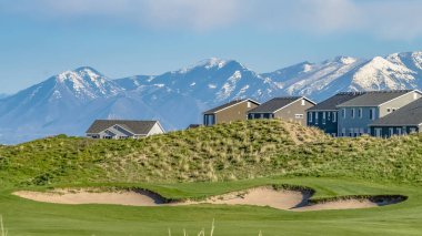 Güneşli bir günde mavi gökyüzüne karşı yemyeşil otlar ve evler ile Panorama Hill