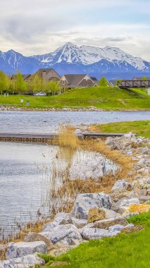 Dikey uzun çerçeve Kıyıda kayalar ve parlak yeşil otlar ile doğal bir göl üzerinde Ahşap güverte