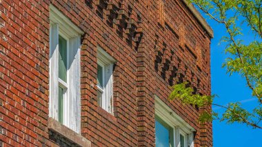 Panorama çerçevesi Önünde parlak yeşillik olan kırmızı tuğla bir binanın dış kısmını kapatın