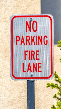 Dikey uzun boylu Hayır Park Fire Lane işareti arka planda bir ağaç ve duvar ile
