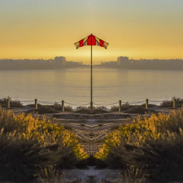 Imgae of a reflected flag on the shore of San Diego with sunset on a clear day — Stock Photo, Image