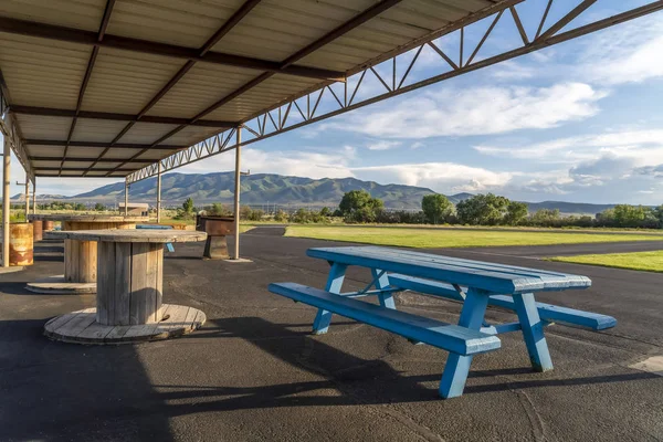 Picnic area with spool tables and blue wooden tables under a pavilion