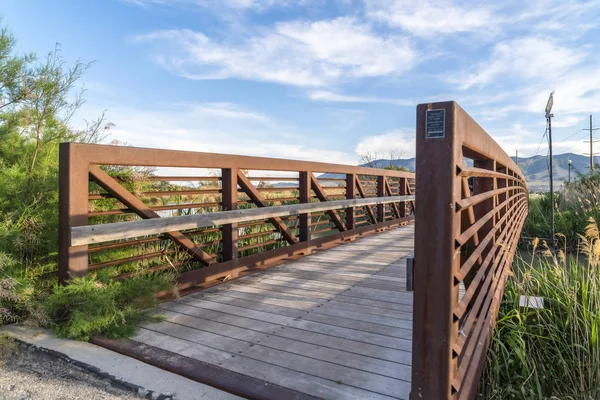 湖の上に木製のデッキと金属ガードレールを備えた橋の晴れた日の眺め — ストック写真