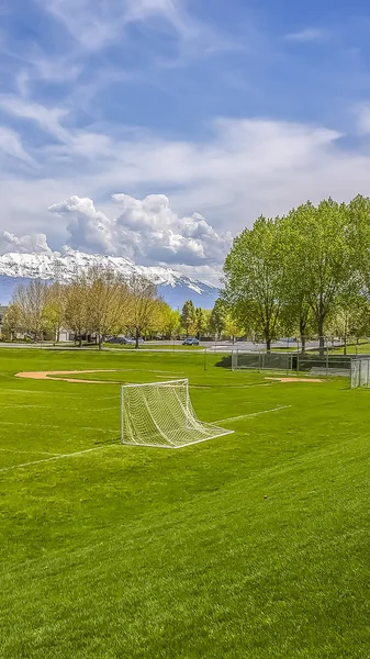 Terrain de football et de baseball vertical avec des arbres luxuriants et des bâtiments en arrière-plan — Photo