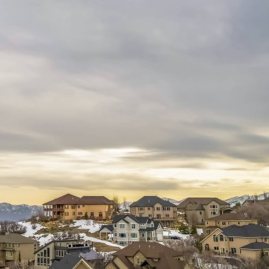 Kare çerçeve Gün batımında bulutlu gökyüzüne karşı karlı bir dağda evlerin Manzara kış görünümü