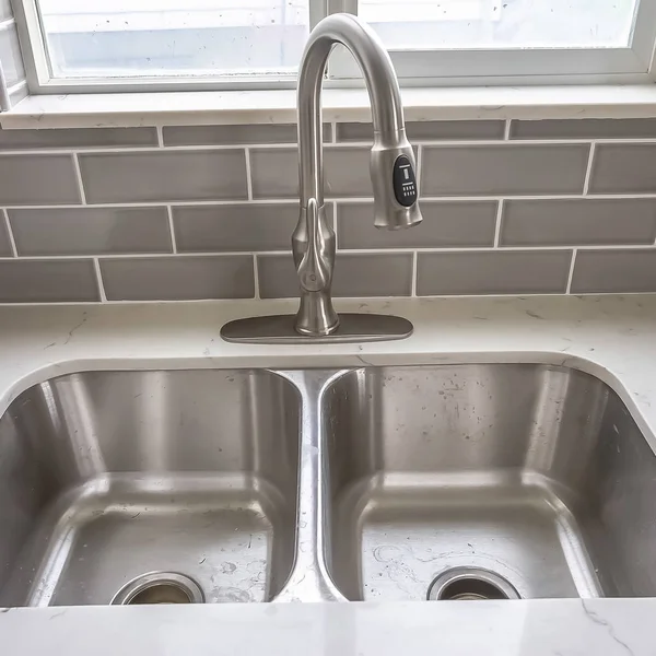 Square frame Double bowl stainless steel sink undermounted on the white kitchen countertop — Stock Photo, Image