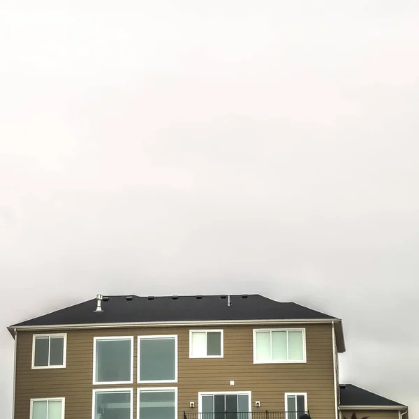 Quadratischer Rahmen heller und wolkengefüllter Himmel über einem Wohnhaus mit braunem horizontalen Wandanschluss — Stockfoto