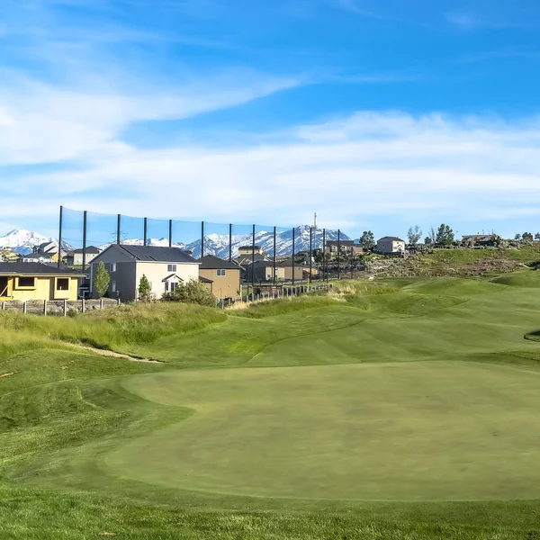Campo de golf cuadrado y casas bajo el cielo azul con nubes vistas en un día soleado — Foto de Stock