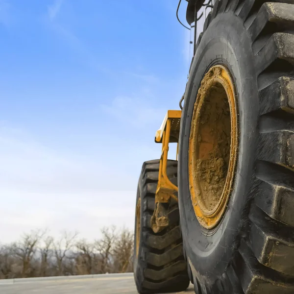 Close up view of the huge black rubber tires of a yellow construction vehicle