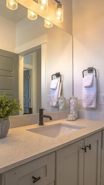 Függőleges tükör és a hiúság egység belsejében egy fürdőszoba, fehér fal és barna fa padló — Stock Fotó